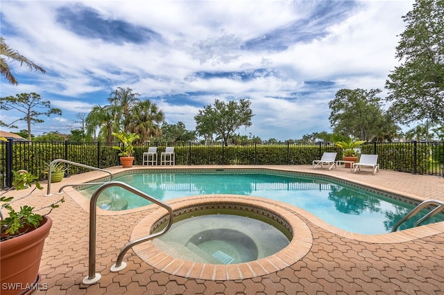view of pool with a fenced in pool, fence, an in ground hot tub, and a patio area