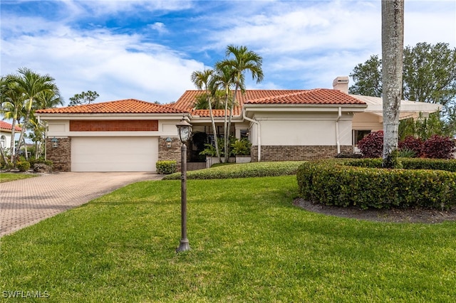 mediterranean / spanish-style house with a tiled roof, driveway, a chimney, a front lawn, and an attached garage