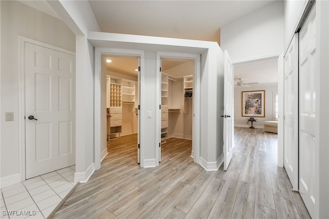 unfurnished bedroom featuring a closet, light wood finished floors, a walk in closet, and baseboards