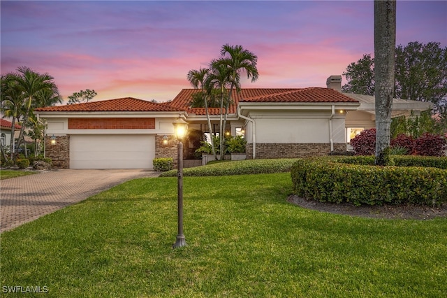view of front facade featuring a front lawn, a garage, a chimney, decorative driveway, and a tiled roof
