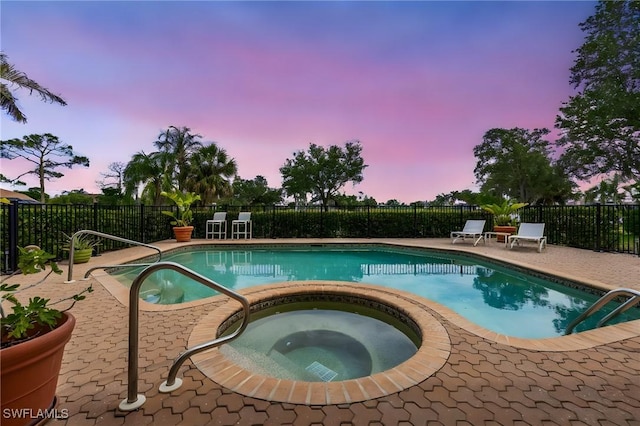 view of swimming pool featuring fence, an in ground hot tub, a fenced in pool, and a patio