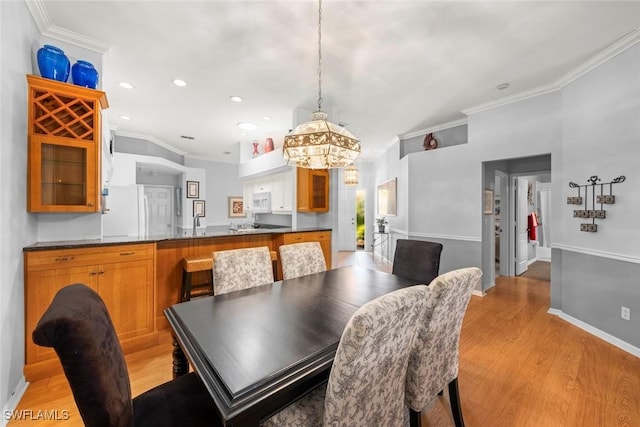 dining space with ornamental molding, light wood-style flooring, a chandelier, recessed lighting, and baseboards