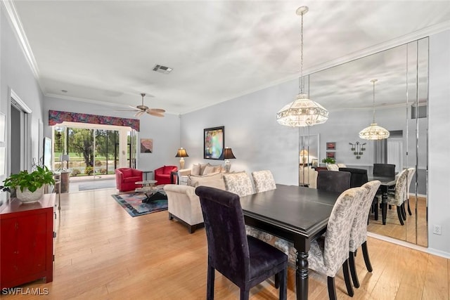 dining room with light wood-type flooring, a ceiling fan, and crown molding