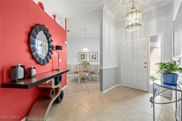 entryway featuring crown molding, light tile patterned floors, a chandelier, and baseboards