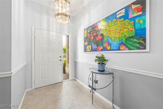 entrance foyer with a chandelier, tile patterned floors, and baseboards