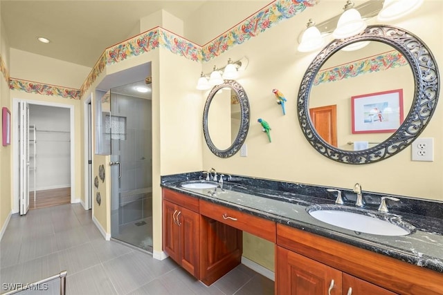 bathroom featuring a shower stall, double vanity, a walk in closet, baseboards, and tile patterned floors