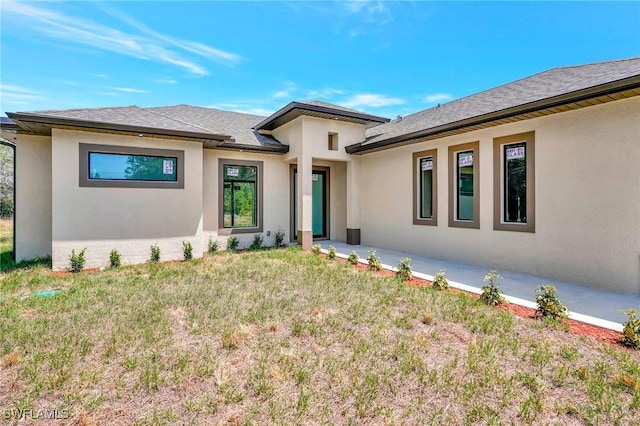 3518 50th St W, Lehigh Acres, FL 33971 - prairie-style house with a front lawn, roof with shingles, and stucco siding