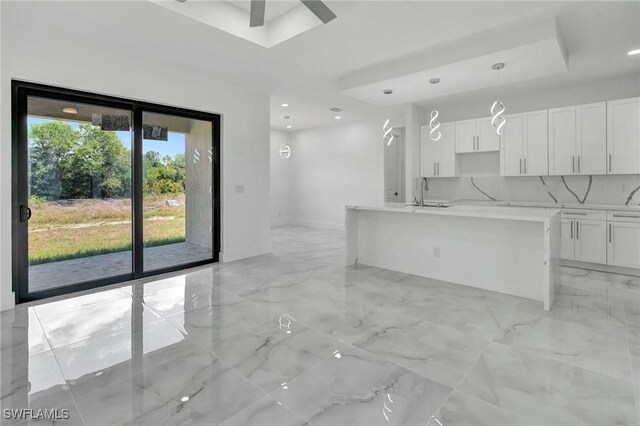 3518 50th St W, Lehigh Acres, FL 33971 - unfurnished living room with marble finish floor, ceiling fan, recessed lighting, a tray ceiling, and a sink