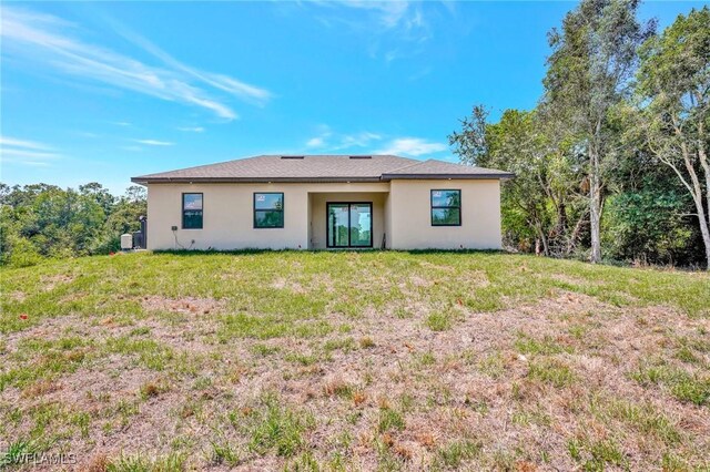 3518 50th St W, Lehigh Acres, FL 33971 - rear view of house with stucco siding and a yard