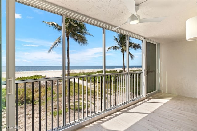 unfurnished sunroom featuring a water view, a beach view, and plenty of natural light