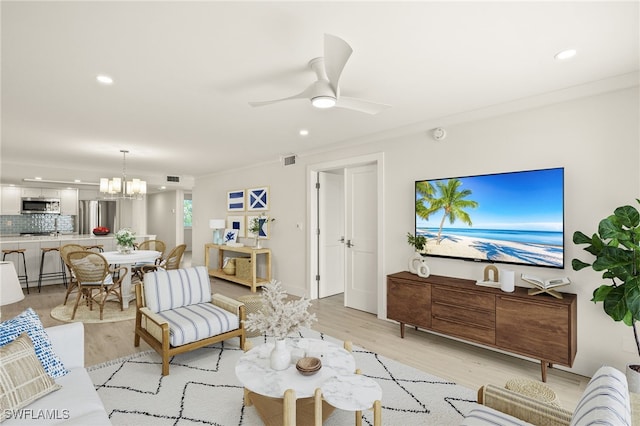 living area featuring recessed lighting, visible vents, light wood-type flooring, and ceiling fan with notable chandelier