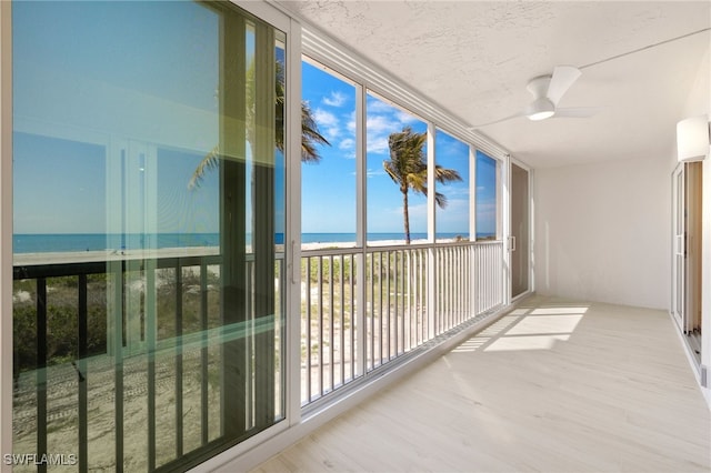unfurnished sunroom featuring a water view and a beach view