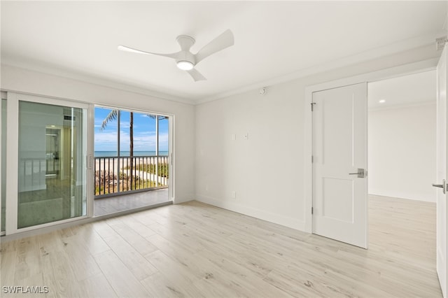 empty room featuring a water view, baseboards, light wood-type flooring, and a ceiling fan