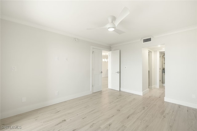 spare room featuring crown molding, visible vents, light wood-style flooring, and a ceiling fan