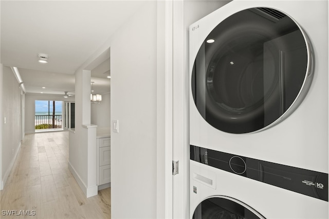 clothes washing area with recessed lighting, baseboards, stacked washer and dryer, light wood-style floors, and laundry area