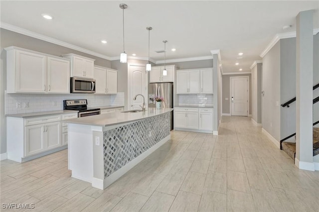 kitchen featuring white cabinets, appliances with stainless steel finishes, a sink, tasteful backsplash, and a center island with sink
