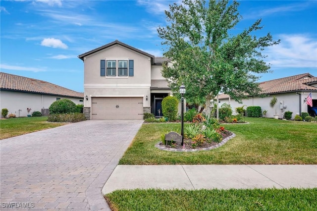 traditional-style house with stone siding, a front yard, decorative driveway, stucco siding, and an attached garage