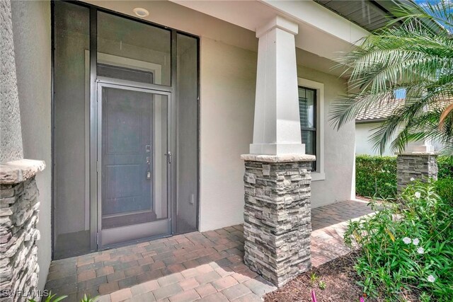 entrance to property featuring a porch and stucco siding