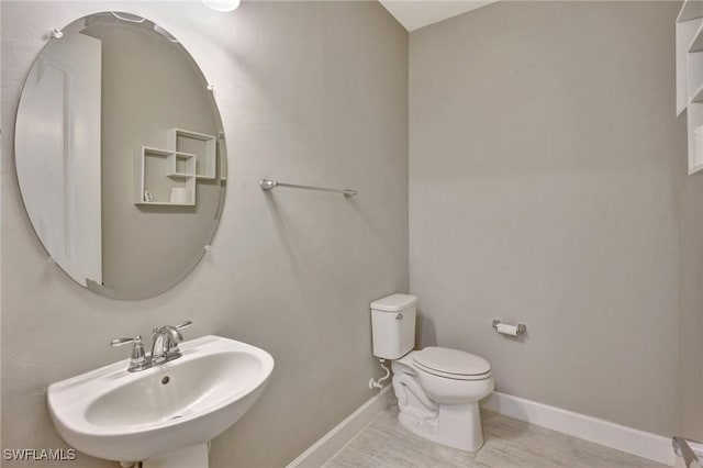 bathroom with baseboards, a sink, and toilet