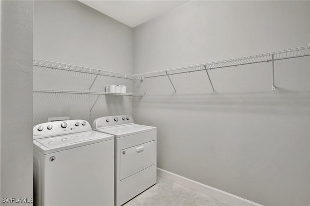 clothes washing area with baseboards, laundry area, and washer and clothes dryer