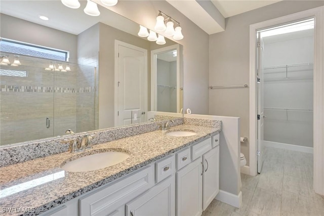 full bath featuring a sink, a shower stall, toilet, and double vanity