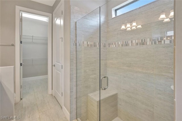 bathroom featuring a spacious closet and a shower stall