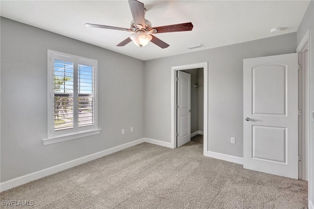 unfurnished bedroom with visible vents, baseboards, carpet floors, and a walk in closet