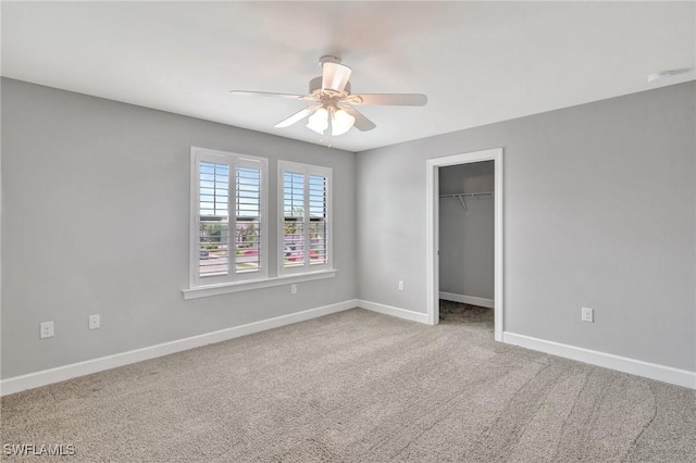 unfurnished bedroom featuring a ceiling fan, baseboards, a closet, a spacious closet, and carpet flooring