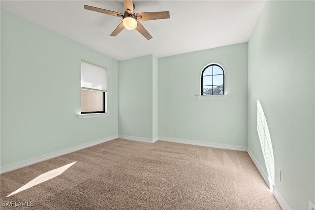 carpeted spare room with baseboards and a ceiling fan