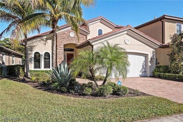 mediterranean / spanish-style house with a garage, stucco siding, decorative driveway, and a front yard