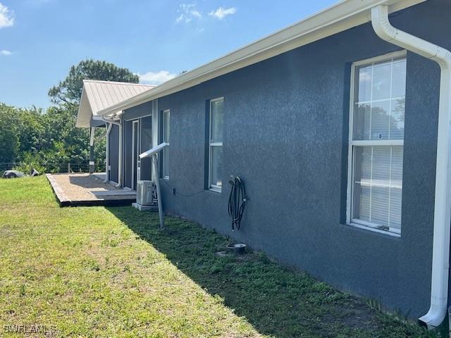 7834 15th Pl, Labelle, FL 33935 - view of property exterior with a lawn, metal roof, and stucco siding