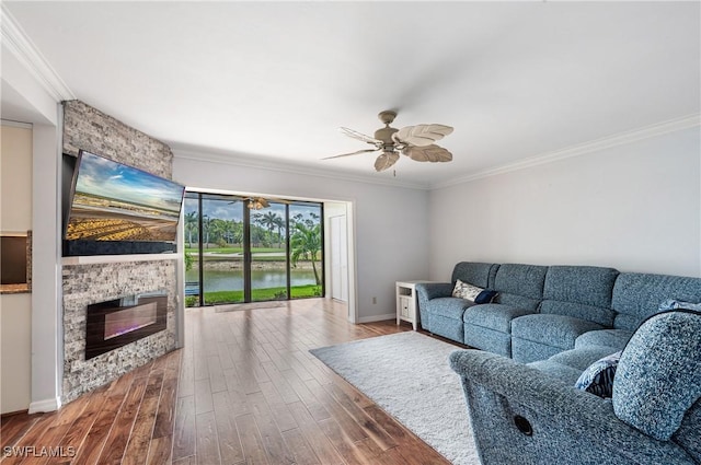 living area featuring baseboards, ornamental molding, a fireplace, and wood finished floors