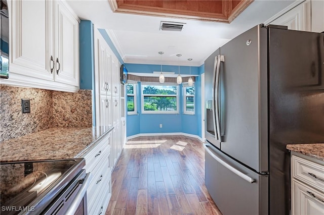 kitchen with visible vents, crown molding, hardwood / wood-style flooring, backsplash, and appliances with stainless steel finishes