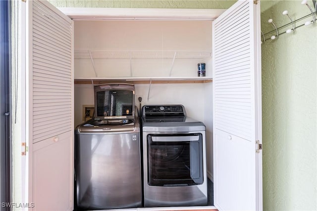 laundry room with laundry area, a textured wall, and separate washer and dryer