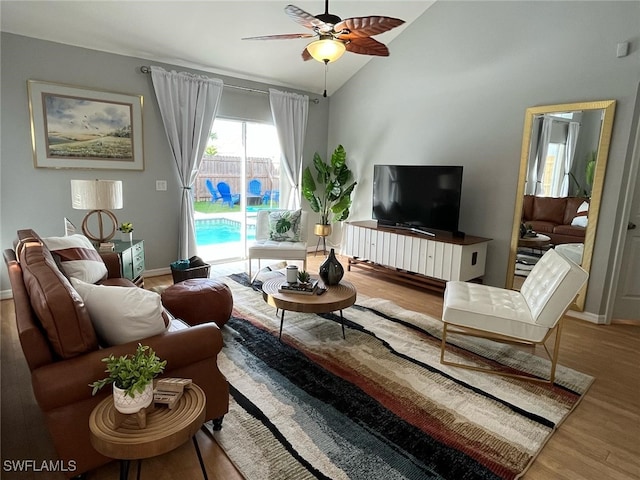living area with baseboards, a ceiling fan, lofted ceiling, and wood finished floors