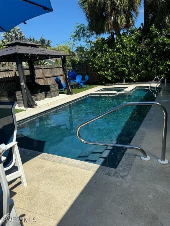 view of swimming pool featuring a gazebo, a fenced backyard, a pool with connected hot tub, and a patio