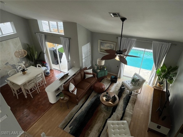 living area with a ceiling fan, visible vents, and wood finished floors