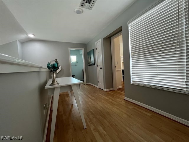 interior space with baseboards, visible vents, wood finished floors, and vaulted ceiling