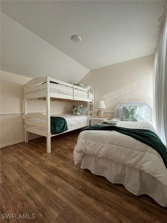 bedroom with baseboards, wood finished floors, and vaulted ceiling