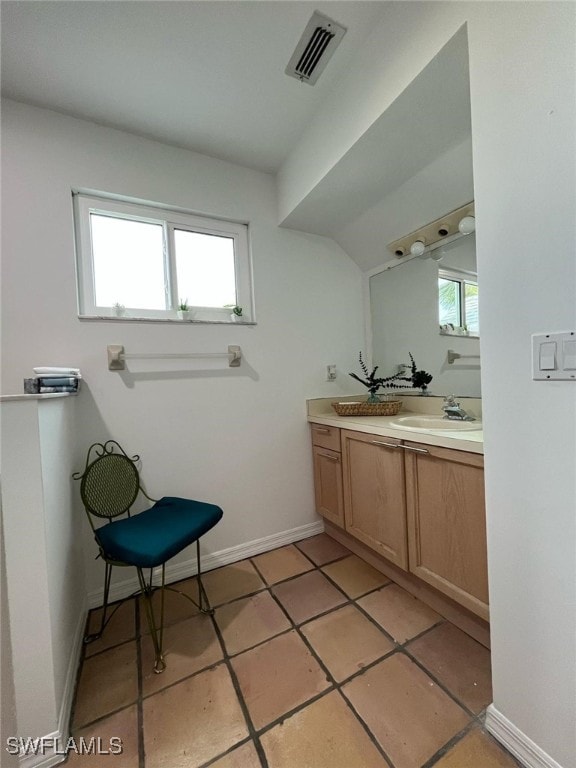 bathroom featuring visible vents, tile patterned flooring, vanity, baseboards, and vaulted ceiling