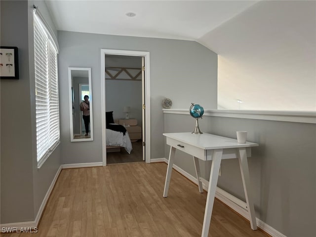 hall with baseboards, wood finished floors, and lofted ceiling