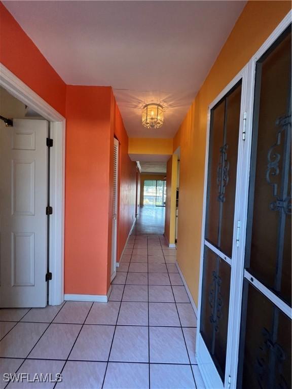 1016 SE 46th St Unit 102, Cape Coral, FL 33904 - hallway with baseboards, a notable chandelier, and light tile patterned floors