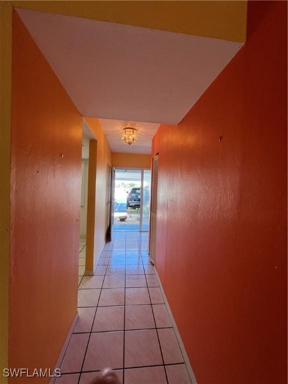 1016 SE 46th St Unit 102, Cape Coral, FL 33904 - corridor featuring an inviting chandelier, baseboards, and light tile patterned flooring