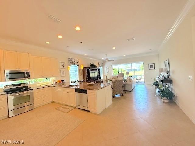 kitchen with a sink, a peninsula, open floor plan, ornamental molding, and stainless steel appliances