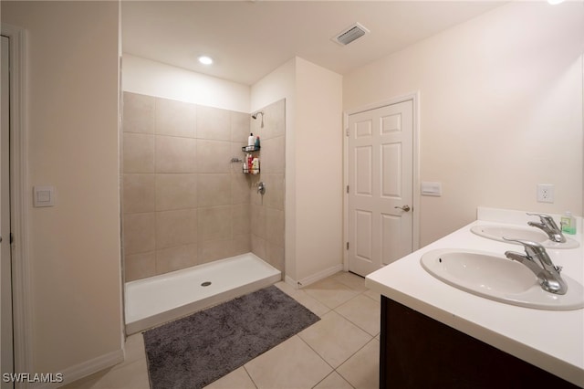 full bathroom featuring visible vents, a tile shower, a sink, and tile patterned flooring
