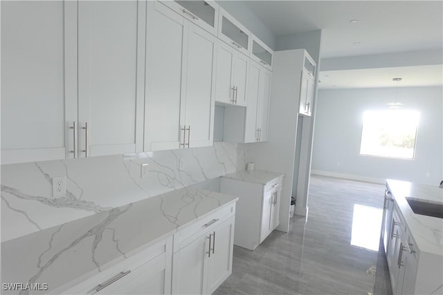 224 Preston St, Lehigh Acres, FL 33974 - kitchen featuring light stone counters, a sink, white cabinetry, and glass insert cabinets