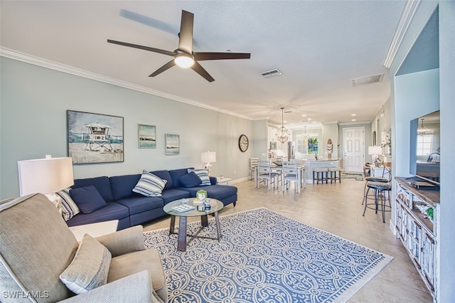 living room with visible vents, ornamental molding, baseboards, and ceiling fan with notable chandelier