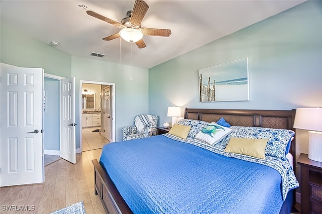 bedroom featuring visible vents, wood finished floors, baseboards, ceiling fan, and ensuite bath