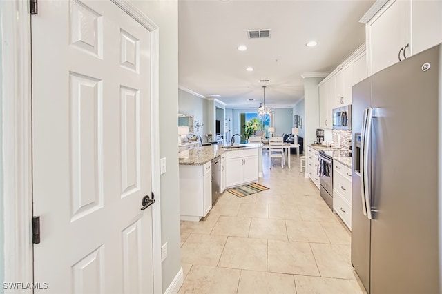kitchen featuring visible vents, crown molding, open floor plan, a sink, and stainless steel appliances