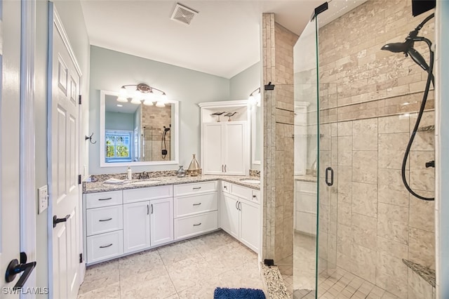 full bath featuring visible vents, double vanity, a sink, and a shower stall
